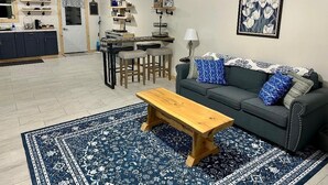 A living room with a dark green sofa, blue patterned cushions, a wooden coffee table, and a blue and white patterned rug. - Whitsendsport  unit 4  1 bedroom & queen pull out  couch on  50 acres Smithfield (Smithfield)
