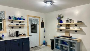 A kitchen with dark blue cabinets, a white countertop, and shelves with various items. - Whitsendsport  unit 4  1 bedroom & queen pull out  couch on  50 acres Smithfield (Smithfield)