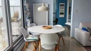 Un comedor moderno con una mesa redonda, sillas blancas y una bandeja de madera.
