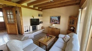 A living room with a sofa, a coffee table, a TV, and a painting on the wall.