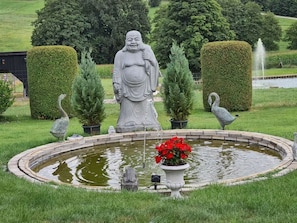 A garden with a pond, a statue, and two bird sculptures.