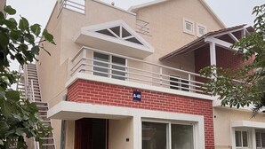 Una casa a due piani con un balcone, una scala a vista e un cartello con il numero civico A-40.