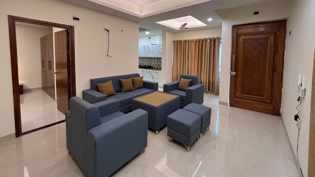 A modern living room with a sofa set, ottomans, a coffee table, and a ceiling fan.