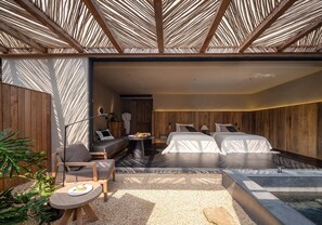 A modern bedroom with a large bed, a small seating area, and a water feature. - Weizhou Island Coral Reef Hotel (Beihai)