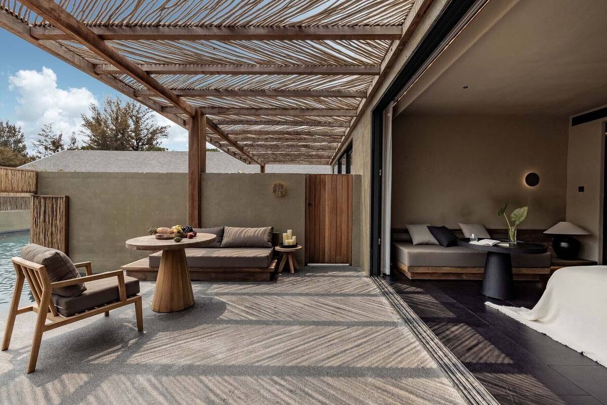 A modern outdoor lounge area with a pool, wooden furniture, and a covered seating area.