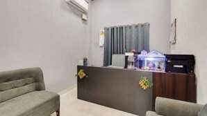 A reception area with a dark reception desk, a fish tank, and two green sofas. - Collection O Gudalur Lake Chennai (Chennai)