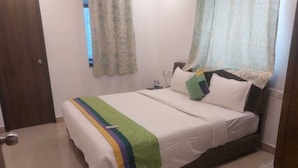 A bedroom with a bed, a nightstand, a window with curtains, and a door. - Collection O Gudalur Lake Chennai (Chennai)