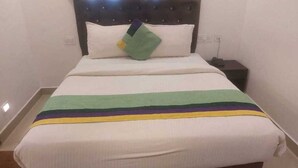 A bed with a striped bedspread and a pillow. - Collection O Gudalur Lake Chennai (Chennai)