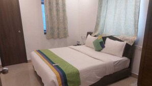 A bedroom with a bed, pillows, a bedside table, and a window with curtains. - Collection O Gudalur Lake Chennai (Chennai)