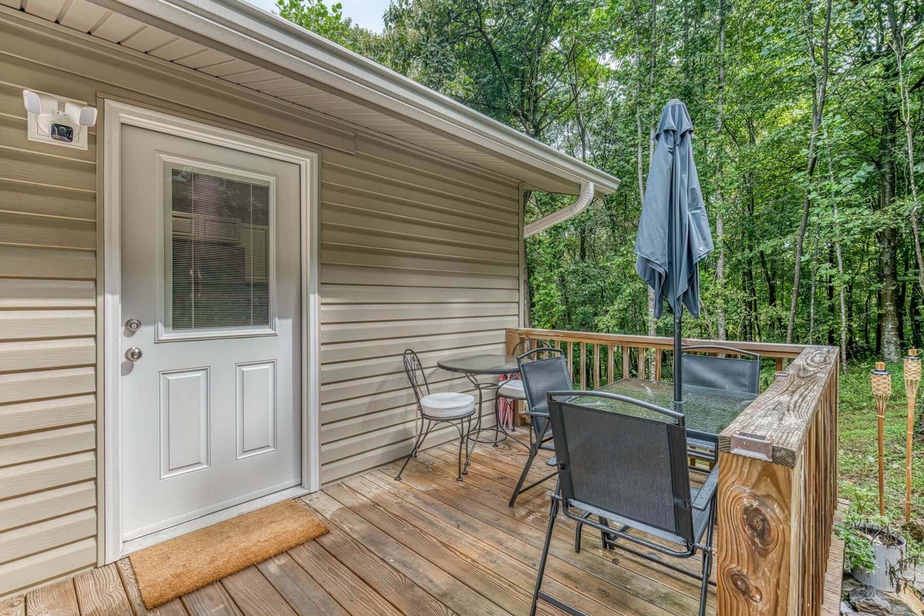 A wooden deck with a table and chairs, a covered patio area, and a door with a window.