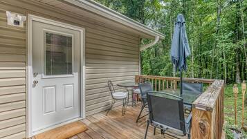 A wooden deck with a table and chairs, a covered patio area, and a door with a window.