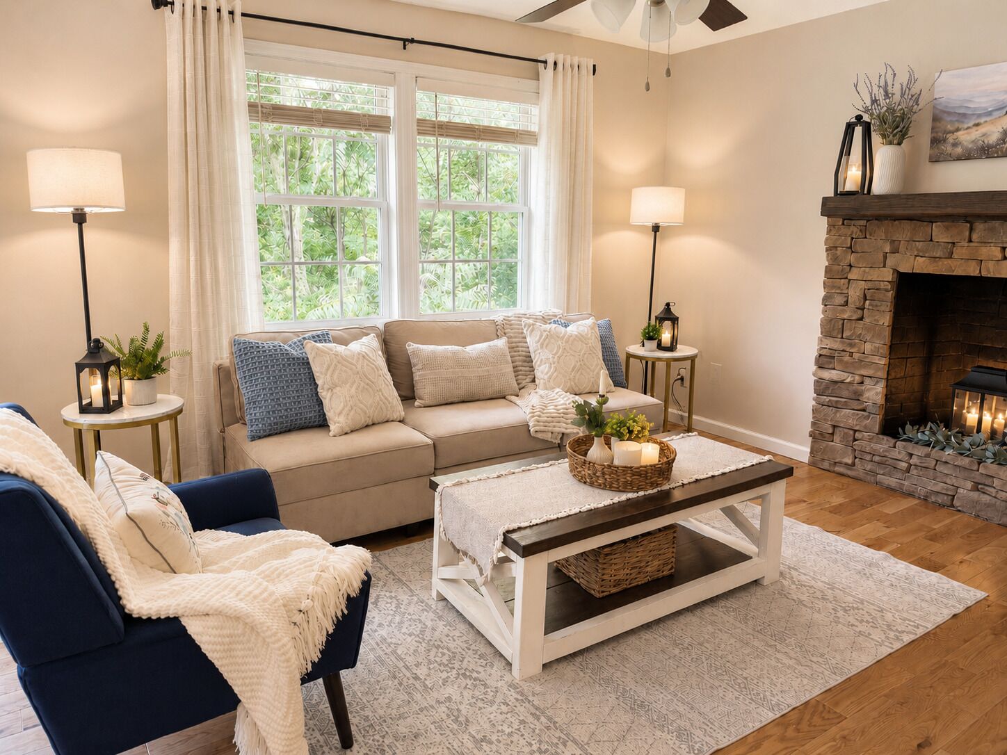 Sala de estar con sofá, sillón, mesa de centro, chimenea y dos ventanas con cortinas.