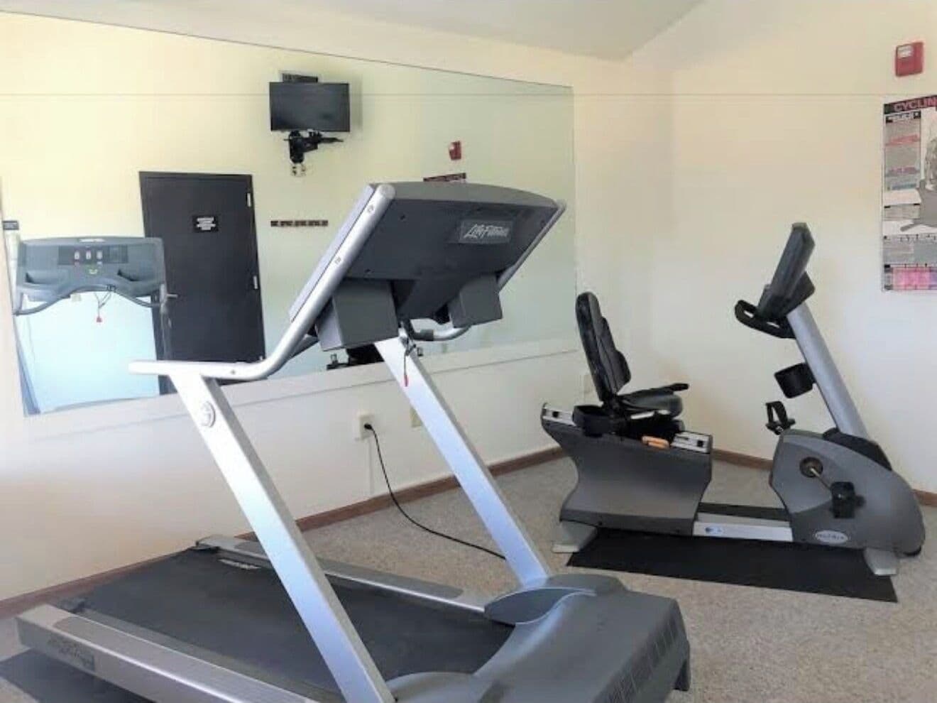 Ein Fitnessraum mit Laufbändern und einer Spiegelwand.