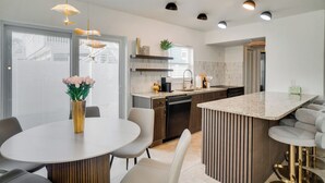 Una cuina moderna amb una illa central, electrodomèstics integrats i il·luminació penjant.