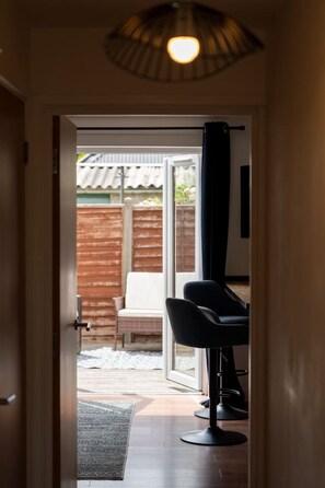 A hallway leading to a room with a large window, a chair, and a ceiling light fixture. - 3 BR Home For 6 | Oxford w/Parking (Marston)