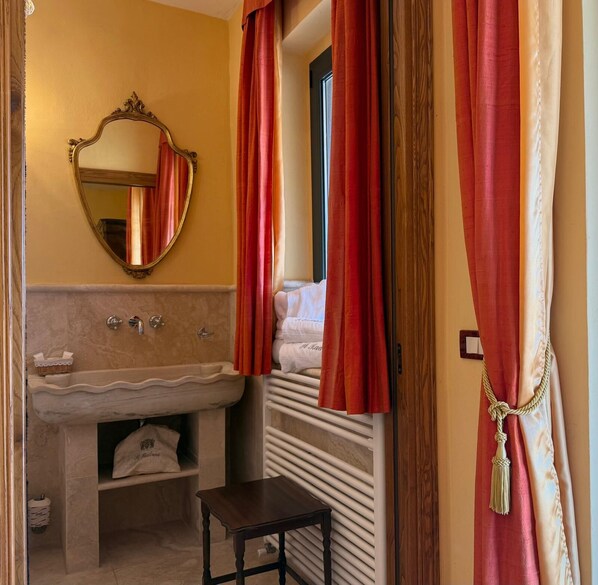 A bathroom with a marble sink, a mirror, and red curtains. - Tuscany Boutique Agriturismo Hotel, pet friendly. (Manciano Marsiliana)