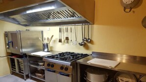 Uma cozinha comercial com eletrodomésticos de aço inoxidável, incluindo fogão, forno e geladeira.