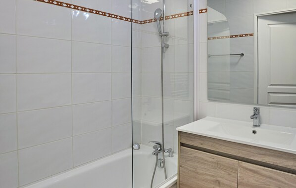 A modern bathroom with a glass-enclosed shower, a white sink, and wooden cabinets. - Residence Odalys Domaine Iratzia (Saint-Jean-de-Luz)
