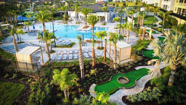 Ein Resort mit großem Pool, Liegestühlen, Palmen und einem gepflegten Garten.
