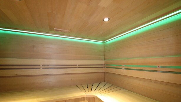 A sauna with wooden walls and benches, green lighting, and a ceiling light. - Dalerveen Apartment With Sauna for 7 (Dalerveen)