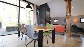 A dining area with a wooden table and chairs, large windows, and a view of the outdoors. - Dalerveen Apartment With Sauna for 7 (Dalerveen)