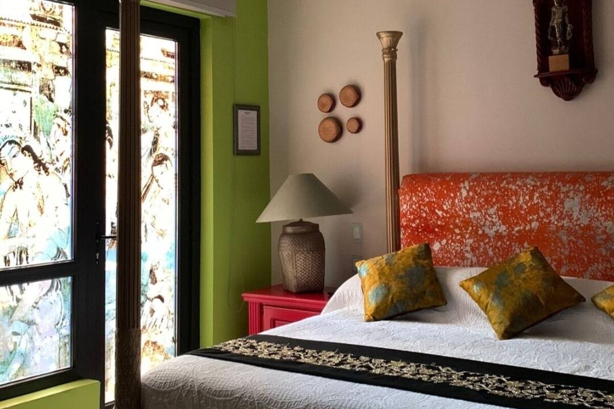 Een slaapkamer met een bed, een raam, een lamp en een plafondventilator.