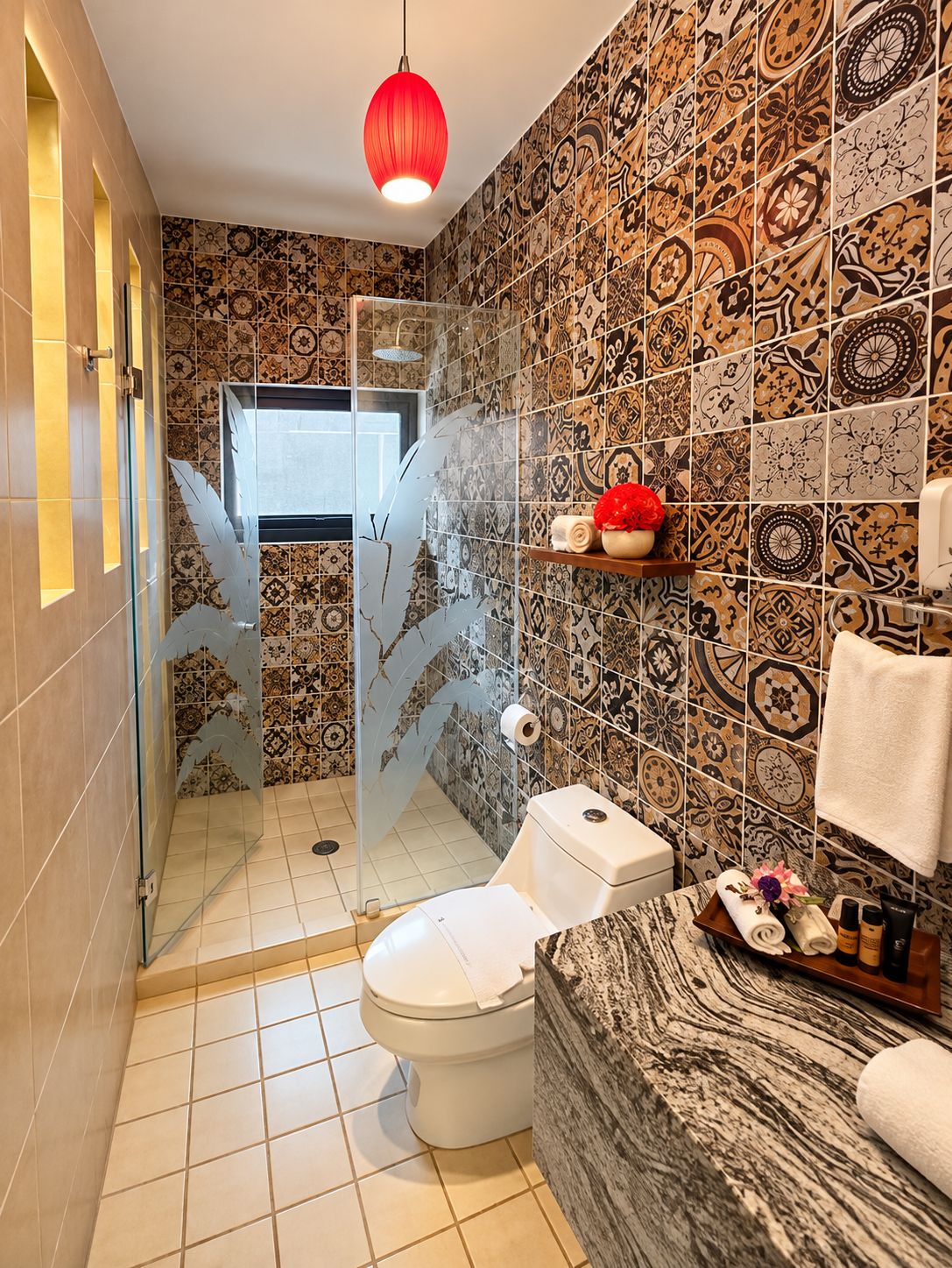 A bathroom with patterned tiles, a toilet, a shower with a glass door, and a red pendant light.