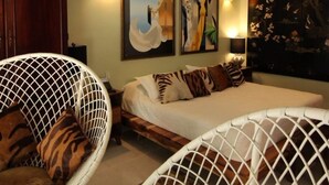 Une chambre à coucher comprenant un lit, deux tableaux accrochés au mur, un ventilateur de plafond et un luminaire suspendu.