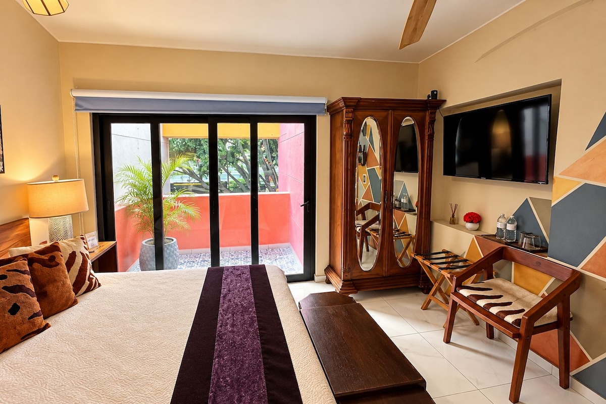 Ein Hotelzimmer mit Bett, Fernseher, Holzschrank und einem Balkon mit Blick.