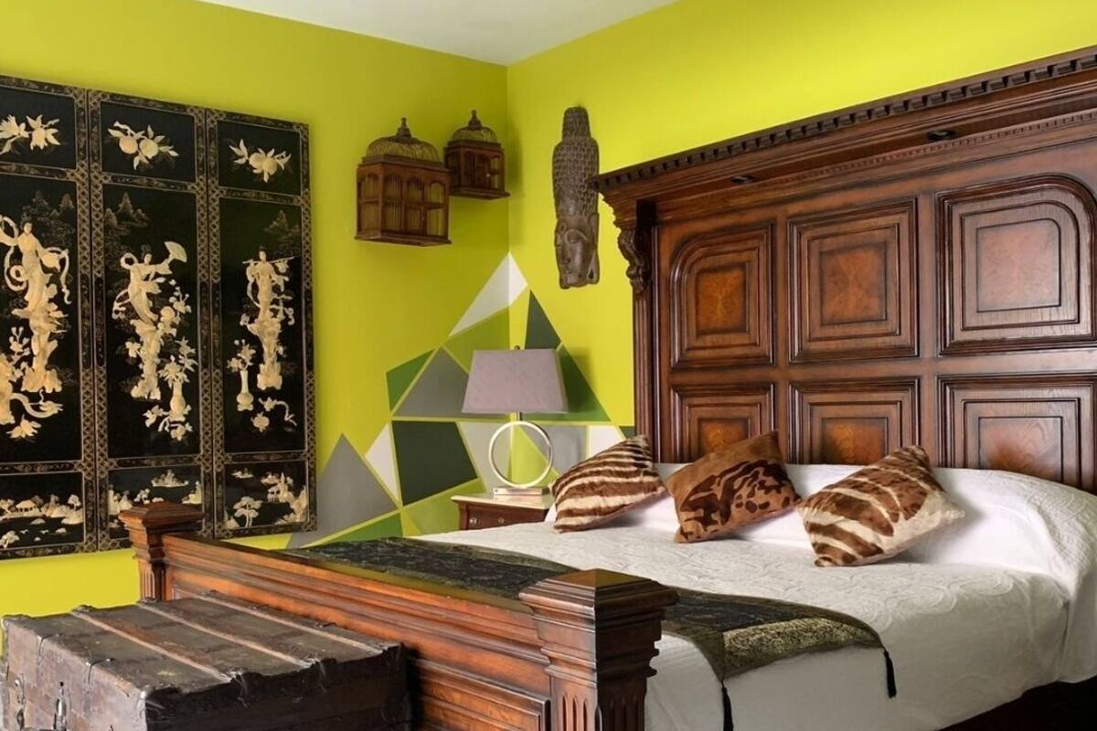 Een slaapkamer met een houten bed, een nachtkastje, een lamp en een decoratief hoofdeinde.