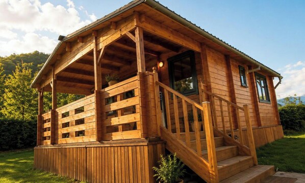 A wooden cabin with a porch, a staircase, and a window.