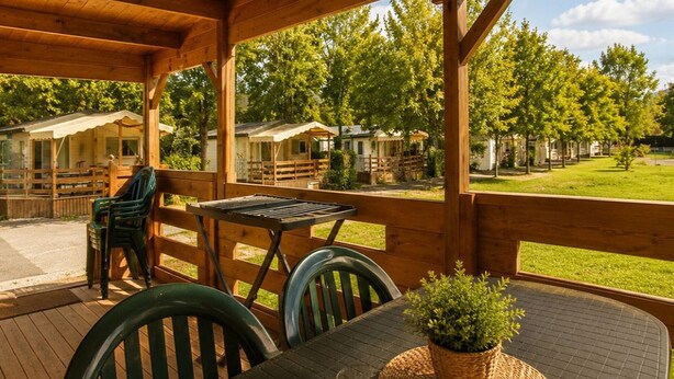 A covered outdoor area with wooden furniture, a table, and chairs.