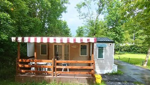 Une petite cabane en bois dotée d’un porche et d’un espace salon abrité, entourée d’une végétation luxuriante.
