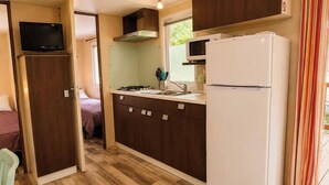 Une cuisine de taille réduite équipée d’un four à micro-ondes, d’une cuisinière et d’un évier.