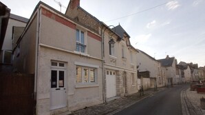 Eine enge Straße gesäumt von traditionellen Gebäuden, mit einer Mischung aus Stein- und Stuckfassaden sowie einem Kopfsteinpflasterweg unter blauem Himmel.