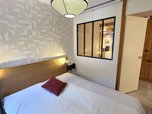 A neatly made bed with a wooden headboard, a red pillow, and a wall-mounted mirror. - Apartment with mountain view - 4 guests (Val-d'Isère)
