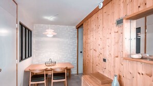 Zona pranzo in legno con tavolo e sedie, lampadario e pensile con specchio e vaso.