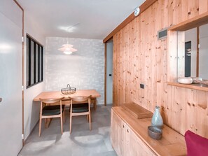 Ein Essbereich mit Holztisch und -stühlen, einer Pendelleuchte und einem Holzschrank mit Spiegel und Vase.