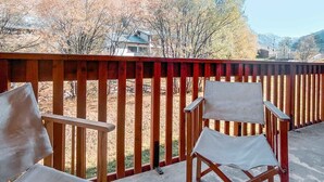 Un balcone con ringhiere in legno e due poltrone in tela.