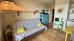 Ein gemütliches Wohnzimmer mit einem gemusterten Sofa, einem kleinen Tisch, einer Mikrowelle und einem dekorativen Wandbild.