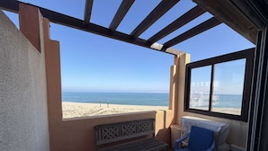 Un balcó amb vista a la platja, una banca i dues cadires.