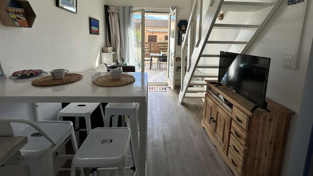 Ein Zimmer mit Essbereich, Fernseher und einer Treppe.