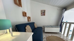 Ein gemütliches Zimmer mit einem blauen Sofa, einem kleinen weißen Tisch und einem gewebten Teppich.