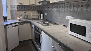 Ett modernt kök med vita skåp, en inbyggd ugn, en mikrovågsugn och en diskmaskin.