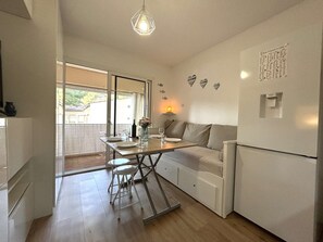 A compact kitchen with a dining area, a refrigerator, and a hanging light fixture. - Calm studio, pool - 2 guests (Sanary-sur-Mer)