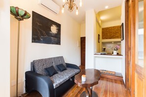 A modern living room with a patterned sofa, a small round table, and a floor lamp. - The Wall Montevideo [001] Studio in the Old Town (Montevideo)