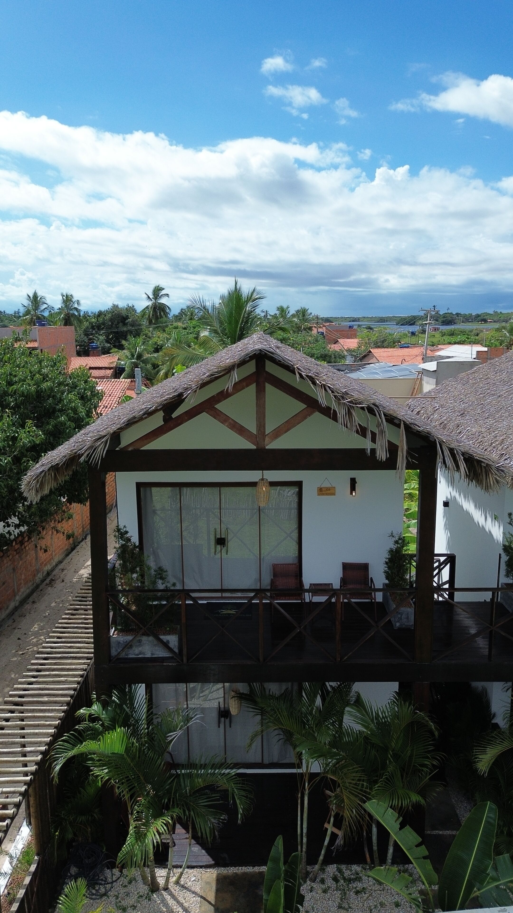 A bungalow with a thatched roof, a balcony, and a view of the surrounding landscape.