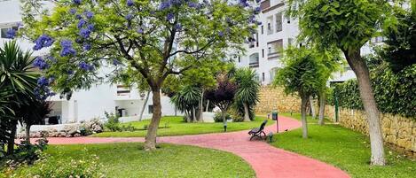 A pathway leading to a building with a stone wall and a bench.