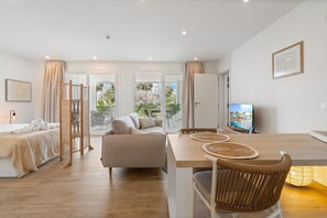 Habitació d'hotel moderna amb llit, sofà, taula de dinar i televisió.