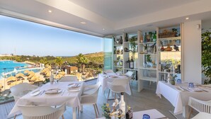 A dining area with tables set for two, overlooking a pool and a scenic landscape. - Stylish 2-pax Stay in Alcazaba Lagoon (Casares)